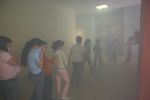 Esercitazione Evacuazione Per Incendio in Una Scuola - I Bambini Escono Dalle Classi E in Mezzo Al Fumo Si Dirigono Ordinatamente Alle Uscite Di Emergenza.